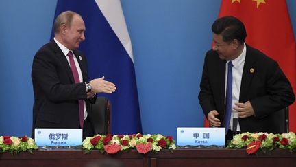 Le président russe Vladimir Poutine s'apprête à serrer la main du président chinois Xi Jinping à Qingdao (Chine), le 10 juin 2018. (WANG ZHAO / AFP)