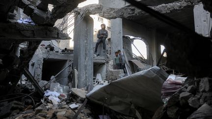 Des garçons gazaouis dans les décombres d'un immeuble détruit par un bombardement israélien, le 18 avril 2025, à Beit Lahia, dans le nord de la bande de Gaza. (BASHAR TALEB / AFP)