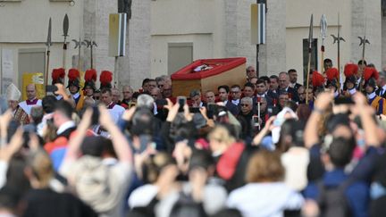 Des personnes attendent de pouvoir voir le cercueil du pape François, alors qu'il est en train d'être transporté vers la basilique Saint-Martin, au Vatican, le 23 avril 2025. (ANDREAS SOLARO / AFP)
