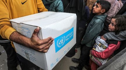 Des Palestiniens font la queue pour recevoir des colis d'aide humanitaire, distribués par l'agence des Nations Unies pour les réfugiés palestiniens, le 21 janvier 2025 à Khan Younès, à Gaza. (ABED RAHIM KHATIB / ANADOLU / AFP)