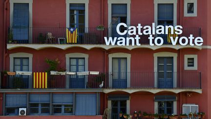 Des drapeaux catalans pro-indépendance et une pancarte indiquant "Nous voulons voter" sur un bâtiment à Gérone, le 15 novembre 2014. Photo d'illustration. (LLUIS GENE / AFP)