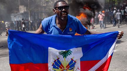 Un homme brandit un drapeau d'Haïti pendant une manifestation exigeant que les autorités prennent des mesures pour faire face à la vague croissante de violences à Port-au-Prince, le 2 avril 2025. (MENTOR DAVID LORENS / EFE via MAXPPP)